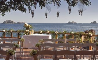 a wedding ceremony taking place on a balcony overlooking the ocean , with chairs set up for guests at Cala de Mar Resort & Spa Ixtapa
