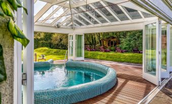 a backyard with a hot tub surrounded by a wooden deck , and several chairs placed around the pool at BrookLodge & Macreddin Village