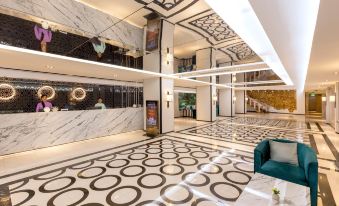 a modern hotel lobby with black and white marble flooring , a reception desk , and a seating area at Pearl Hotel