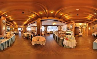 a panoramic view of a restaurant with multiple dining tables and chairs , set up for an event at Hotel Villa Argentina