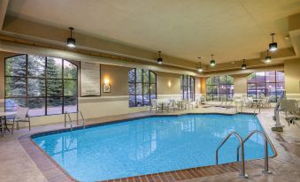 an indoor swimming pool surrounded by lounge chairs , with people enjoying their time in the pool area at Staybridge Suites Milwaukee Airport South