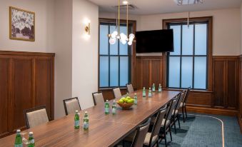 a conference room with a long wooden table and several chairs arranged around it , along with a television mounted on the wall at Hilton Garden Inn Flint Downtown