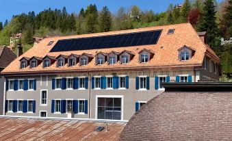 a large , modern building with solar panels on its roof , surrounded by trees and a clear blue sky at Fleur de LIS