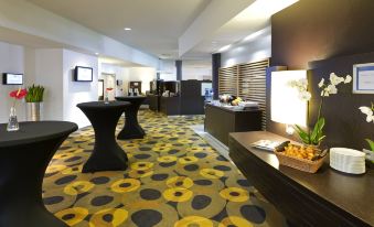 a modern hotel lobby with a large yellow and black carpet , several tables , chairs , and a reception desk at Novotel Leuven Centrum