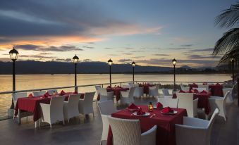 an outdoor dining area with tables and chairs set up for a dinner party , overlooking a body of water at Swiss-Belhotel Silae Palu