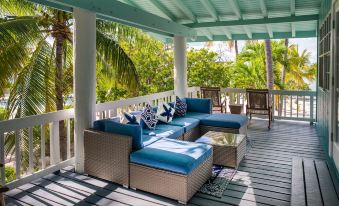 a patio with blue furniture and a couch , surrounded by palm trees and overlooking a river at Lime Tree Bay Resort