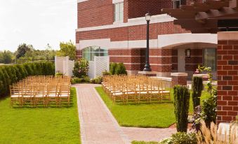 a wedding ceremony taking place in a brick building , with rows of wooden chairs set up for guests at Marriott Boston Quincy