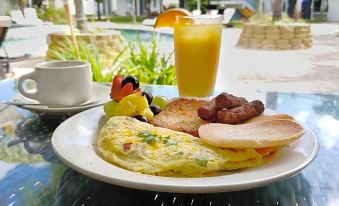 a plate of food with an omelette , fruit , and a drink is displayed on a table at Solace by the Sea