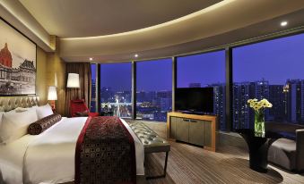 The large room features a bed and windows that offer a nighttime view of the city at Sofitel Guangzhou Sunrich