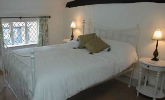 a white bed with a black headboard and footboard , situated in a room with a window and a lamp at The Brocket Arms