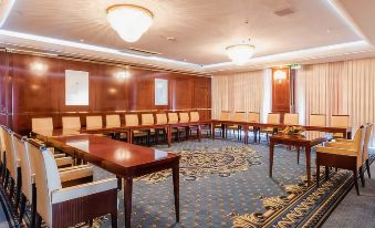 a large conference room with wooden tables and chairs arranged in a semicircle , creating a formal setting at Hotel President Solin