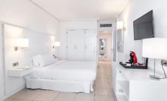 a white bedroom with a large bed , a television , and a kettle on the nightstand at Landmar Costa Los Gigantes