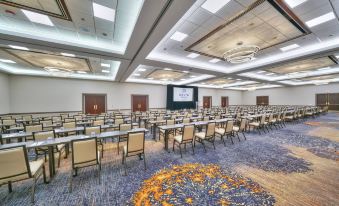 a large conference room with rows of chairs arranged in a semicircle , and a projector screen mounted on the wall at Renaissance Chicago Glenview Suites Hotel