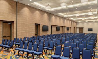 a large conference room with rows of blue chairs arranged in front of a projector screen at Embassy Suites by Hilton South Jordan Salt Lake City