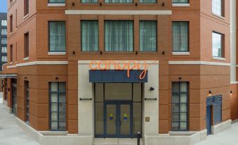 a brick building with a large orange sign above the door , indicating that it is an apartment building at Canopy by Hilton Ithaca Downtown