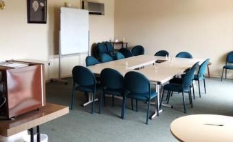 a large , empty conference room with multiple chairs arranged in rows and a whiteboard on the wall at Plainsman Motel
