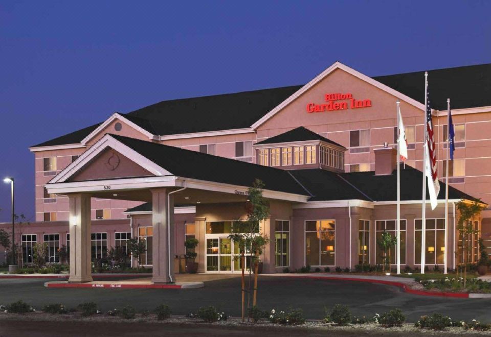 "a large hotel with a red sign that says "" candlewood suites "" is shown at night" at Hilton Garden Inn Clovis