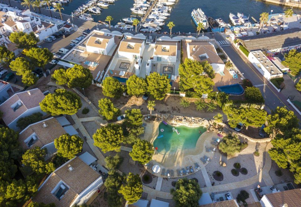 an aerial view of a resort surrounded by trees and buildings , with a pool in the foreground at Lago Resort Menorca Casas del Lago