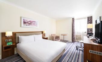 a large , white bed is in a hotel room with blue and white striped carpet at Holiday Inn Leeds - Wakefield M1, Jct.40