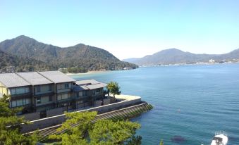 a picturesque view of a waterfront with buildings , trees , and mountains in the background , under a clear blue sky at Sakuraya