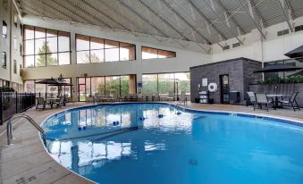 an indoor swimming pool with a large window , surrounded by lounge chairs and tables , in a modern building at The Atrium Hotel on Third