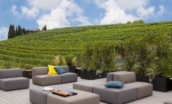 a rooftop terrace with a variety of seating options , including couches and chairs , surrounded by lush greenery and a beautiful view of vineyards at Arborina Relais