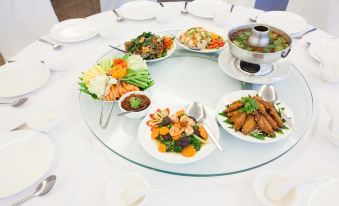 a round dining table with a variety of dishes , including seafood , vegetables , and other food items at Bay Hotel Srinakarin