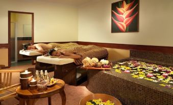 a spa room with two massage tables , one on the left and one on the right , surrounded by various flowers at Lavilla by Holiday Villa Cherating