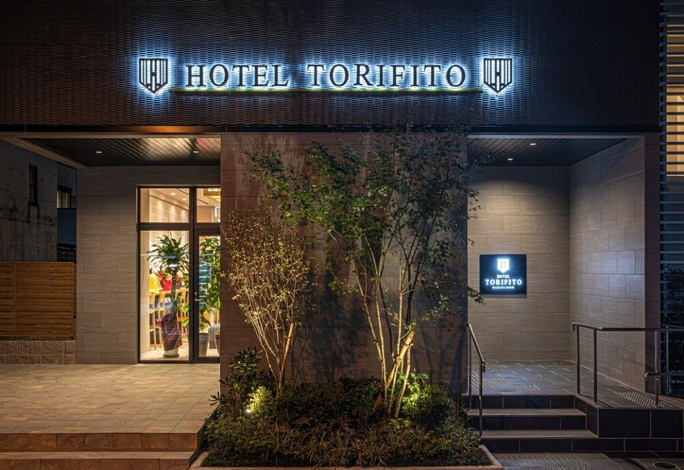 the entrance of a hotel named hotel torfilho , with a sign above it and a tree in the front at Hotel Torifito Hakata Gion