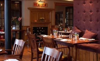 a well - decorated dining room with wooden furniture , including tables and chairs , in front of a fireplace at Manor Hotel