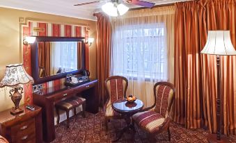a cozy living room with a wooden floor , red curtains , and a large window , as well as a dining table and chairs at Riverside Inn