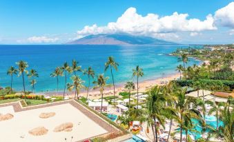 a beautiful beach with palm trees and a pool , as well as a mountainous island in the background at Four Seasons Resort Maui at Wailea