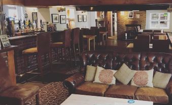 a cozy living room with a brown leather couch , a dining table , and a bar at The Black Bull