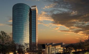 a tall building with the hilton name on it is reflected in its glass facade at Hilton Memphis