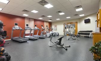 a gym with treadmills , stationary bikes , and other exercise equipment arranged in a line at Hilton Garden Inn Bartlesville