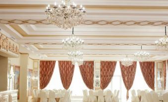 a large , elegant ballroom with white walls and gold accents , decorated with red drapes and chandeliers at "Palazzo"