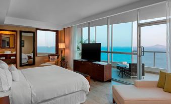 a luxurious hotel room with a large bed , television , and sliding glass doors that open up to the ocean at The Westin Playa Bonita Panama