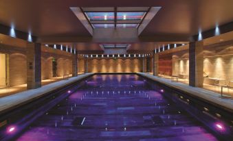 a large indoor pool with purple lights illuminating the area , creating a vibrant and inviting atmosphere at Hotel de Bourgtheroulde, Autograph Collection