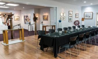 a dining room with a long table covered in a black tablecloth , surrounded by chairs at Rosevears Riverview Hotel