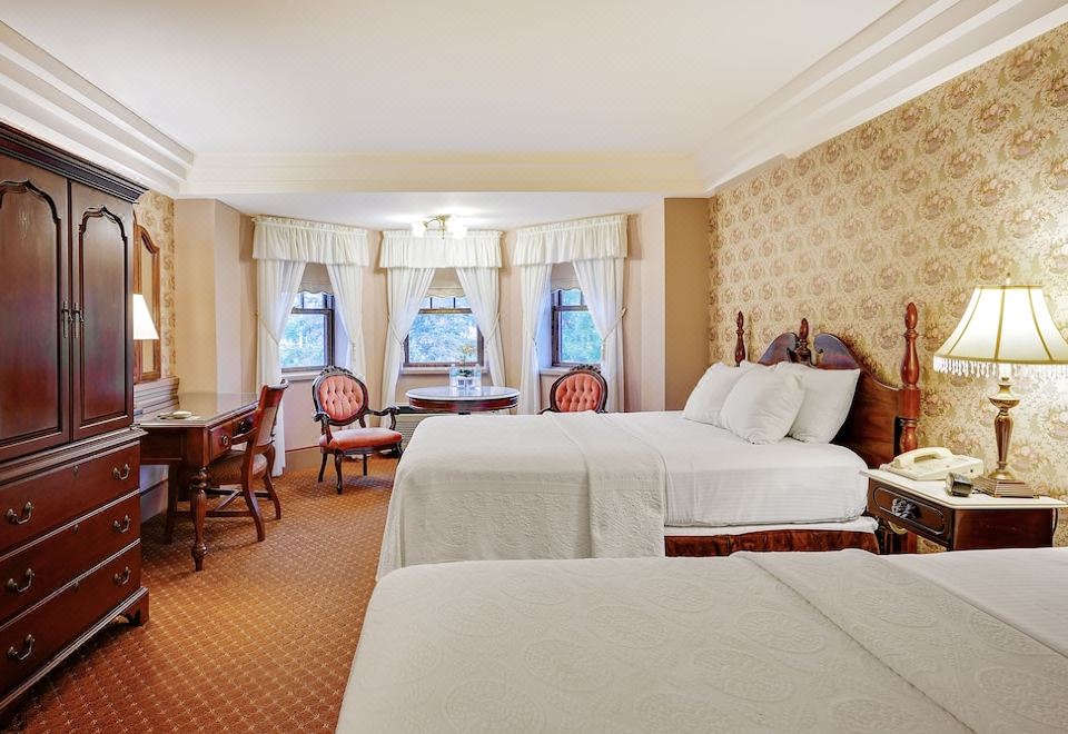 a large hotel room with two beds , white linens , and a view of the city through the windows at The Clarkson Inn