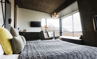 a cozy bedroom with a large bed , a television , and a view of the mountains outside the window at Fosshotel Glacier Lagoon