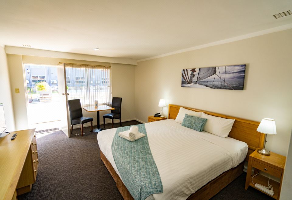 a hotel room with a king - sized bed , a dining table , chairs , and a television at Hospitality Esperance, SureStay Collection by Best Western