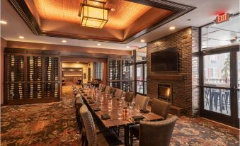 a long dining table with chairs is set up in a room with a fireplace and large windows at The Craftsman Inn & Suites