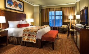 a hotel room with a king - sized bed , a couch , and a tv . also a bathroom visible in the room at Four Winds Casino Resort – New Buffalo