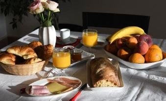 a table is set with a variety of breakfast items , including croissants , fruit , juice , and bread at Le Cercle Chambres climatisées