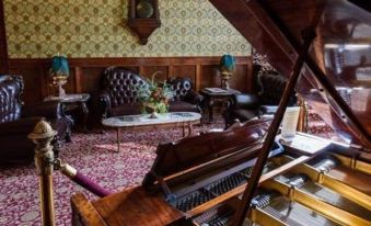 a room with wooden walls and a carpeted floor has a piano in the center at Grand Imperial Hotel