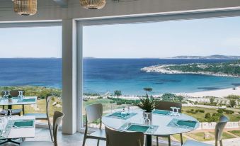 a dining area with a view of the ocean , featuring several tables and chairs arranged for guests at MClub Marmorata