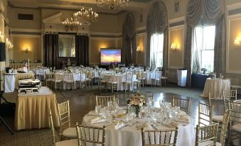 a large banquet hall filled with round tables and chairs , all set for a formal event at Francis Marion Hotel