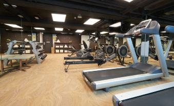 A spacious room contains multiple exercise equipment, including an indoor weight machine positioned in the center at Wharney Hotel