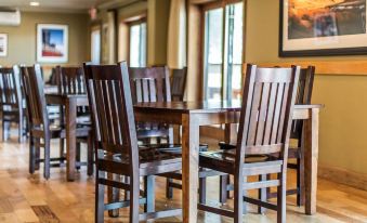 a wooden dining room with a long wooden table and chairs , along with a painting on the wall at Yellowstone Valley Lodge, Ascend Hotel Collection